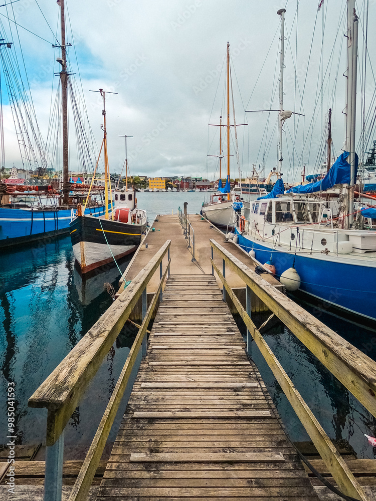 Fototapeta premium Nautical Scene with Dock and Boats Looks Through to Beautiful Views of the Harbor in Tórshavn, the Capital of the Faroe Islands. Streymoy, Faeroe Islands.