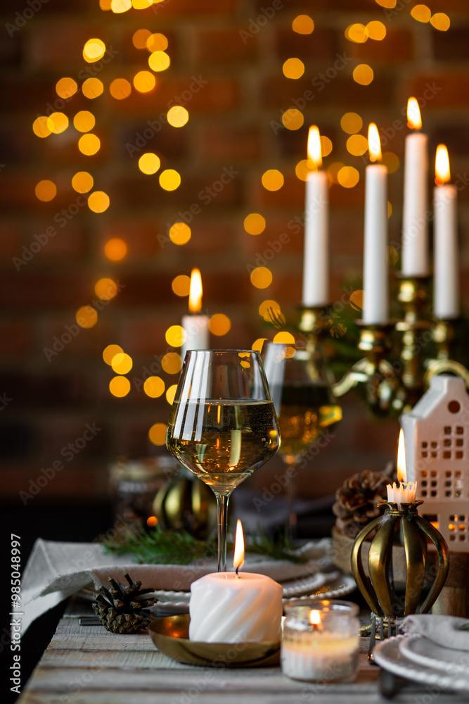 Luxury elegant Christmas dinner table setting with old vintage golden chandelier, candles, fir tree branches, wooden furniture. Porcelain houses as centrepiece, garland with lights on background Luxury elegant Christmas dinner table setting with old vintage golden chandelier, candles, fir tree branches, wooden furniture. Porcelain houses as centrepiece, garland with lights on background