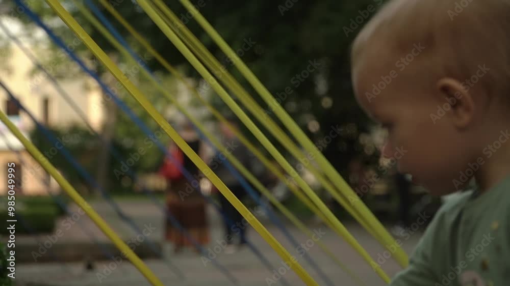 A cute little girl admires the colorful ribbons in the decor of a city park, smiles, looks at the camera, and cheerfully runs to her parent. ukraine A cute little girl admires the colorful ribbons in the decor of a city park, smiles, looks at the camera, and cheerfully runs to her parent. ukraine