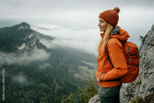 Young Woman in Orange Hiking Jacket in Misty Mountains - Outdoor Adventure and Exploration for Activewear Marketing photo