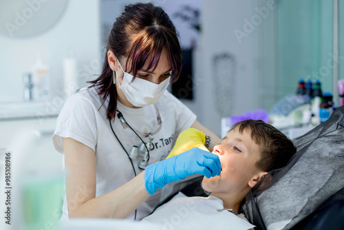 Paediatric dentist putting a cheek retractor on child patient before dental treatment