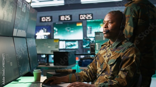 Army specialist working in war room operating surveillance tech, evaluating target data, talking in voice call. Dispatcher keeping in touch with allied troops engaging enemy forces, camera B
