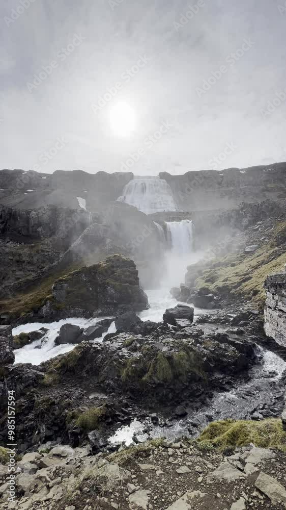 Isafjordur, Iceland - Dynjandi, Fjallfoss, Arnarfjörður, Westfjords cascading waterfall sightseeing location on a grey overcast sun peaking behind clouds Isafjordur, Iceland - Dynjandi, Fjallfoss, Arnarfjörður, Westfjords cascading waterfall sightseeing location on a grey overcast sun peaking behind clouds