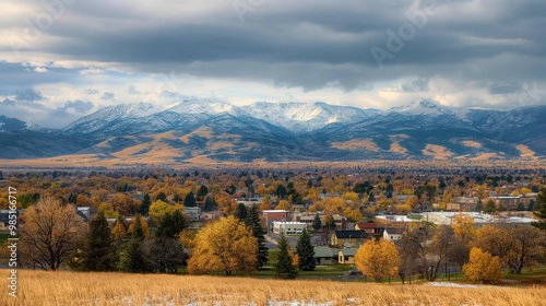 Panoramic landscape of Bozeman town with Bridger mountain range in background. Sky with white clouds. Green trees, buildings, and urban area. Nature and landmark scene.