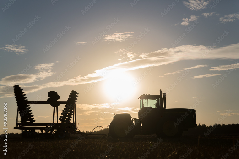 Fototapeta premium Silhouette of a tractor and cultivator