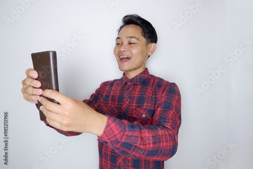 portrait of a handsome Indonesian man having a random expression wearing a checkered red flannel shirt on a white isolated background