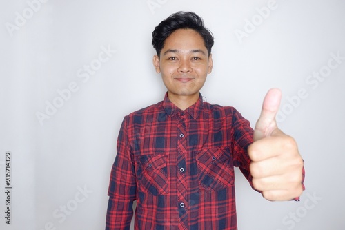 portrait of a handsome Indonesian man having a random expression wearing a checkered red flannel shirt on a white isolated background