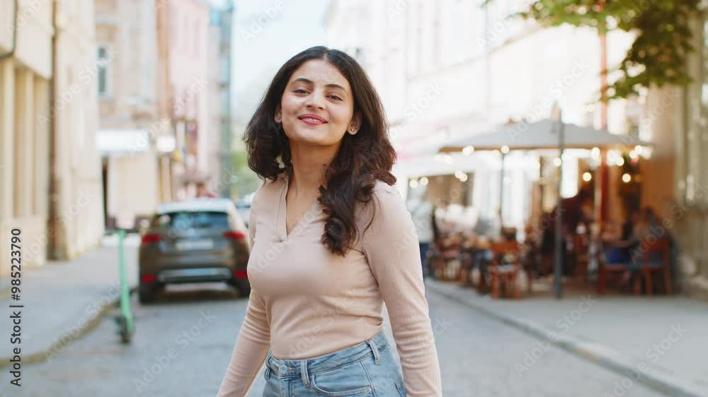 Portrait of happy Indian young woman turning smiling friendly glad expression looking at camera dreaming resting relaxation feel satisfied good news outdoor. Hispanic girl walking on urban city street