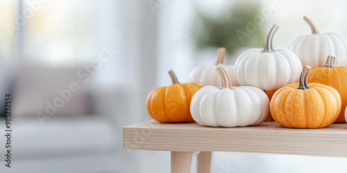 Colorful mini pumpkins are artfully arranged on a light wooden table, creating a cozy and festive autumnal decor in a bright, modern living room.