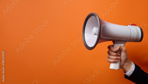 Hand holding a megaphone announces sales and discounts, on a vibrant orange background. Marketing and commercial concept banner with copy space