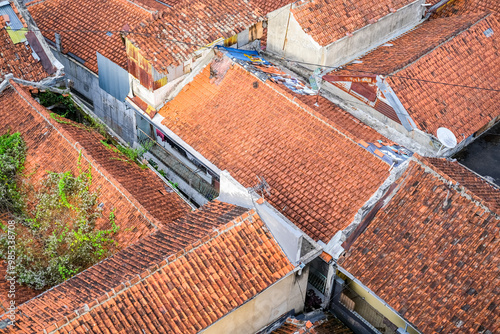 Obraz na płótnie Residential houses in Java, Indonesia, with red-tiled roofs, lush greenery, and a cozy traditional atmosphere. Some roofs have overgrown plants, blending nature with urban living. w salonie