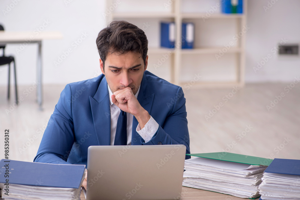 Young male employee and too much work in the office Young male employee and too much work in the office