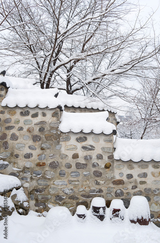 Jung-gu, Seoul, South Korea - February 4, 2013: Snow covered roof tile and crocks(Jangdok) at Namsangol Hanok Village photo