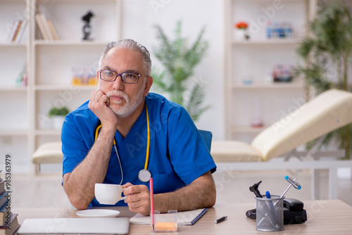 Old male doctor drinking coffee during break