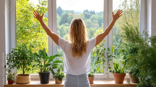 A woman stands by a window, embracing nature with arms wide open, surrounded by lush plants and greenery. Free Download A woman stands by a window, embracing nature with arms wide open, surrounded by lush plants and greenery. - GFXLoad