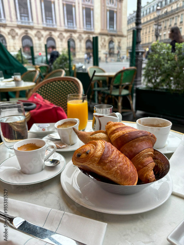 Pain au chocolate and croissant on table with coffee at the terrace with city view, elegant breakfast concept.  