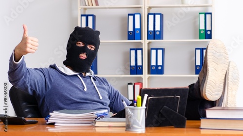 Male thief in balaclava in the office
