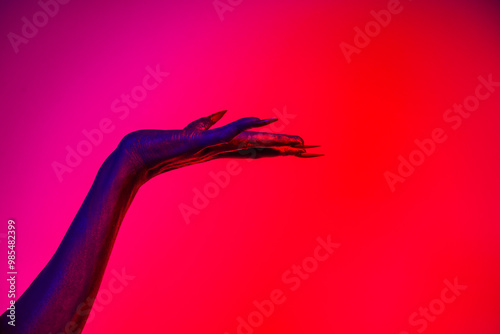 Foto A witch hand with long nails appears against a red fire background, evoking a demonic, monstrous presence