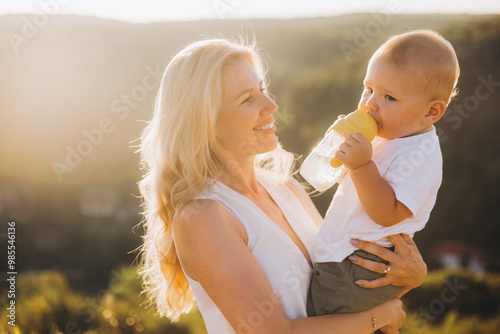 Loving Mother Holding Her Baby Son Outdoors in Warm Golden Sunlight