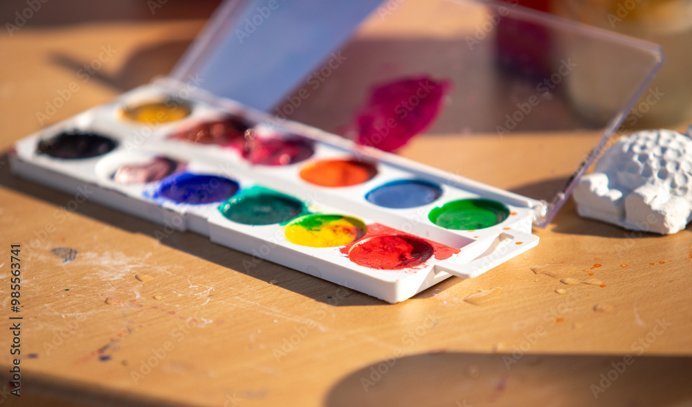 A palette of watercolors is open on a table A palette of watercolors is open on a table