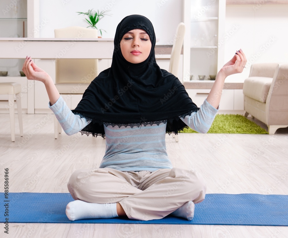 Young woman in hijab doing exercises at home