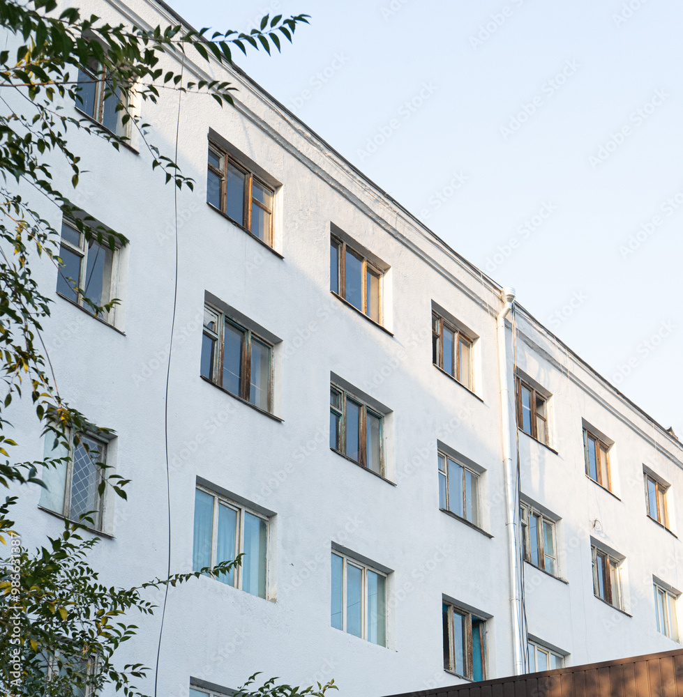 Naklejka premium A modern apartment building bathed in soft daylight, showcasing clean architectural lines and well-maintained exterior. The photo captures the minimalist design and urban living atmosphere 