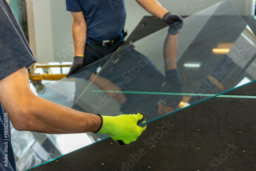 Glaziers place a large pane of glass on a table in the glassworks photo