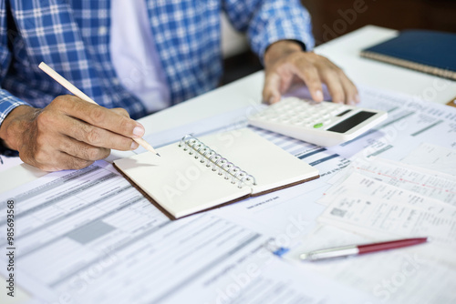 Fototapeta Naklejka Na Ścianę i Meble -  Close-up shot. asian men taking note income and expenses using calculator to calculate receipt and checking business document from small business operation that he own