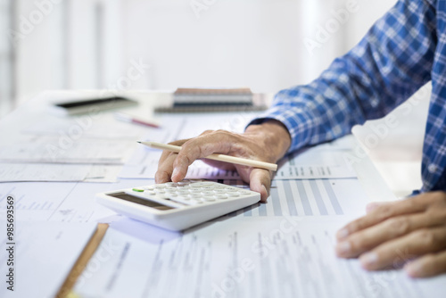 Close-up shot. asian men hand using calculator to calculate income and expenses from small business operations that he owns to recive tax reduction for personal individual Income photo