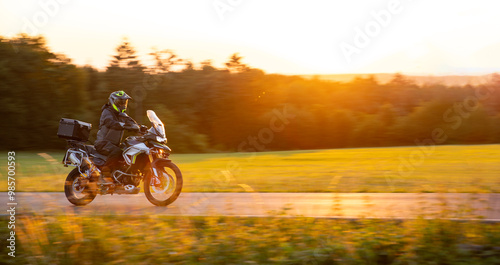 Driver riding motorcycle on empty road during sunset
