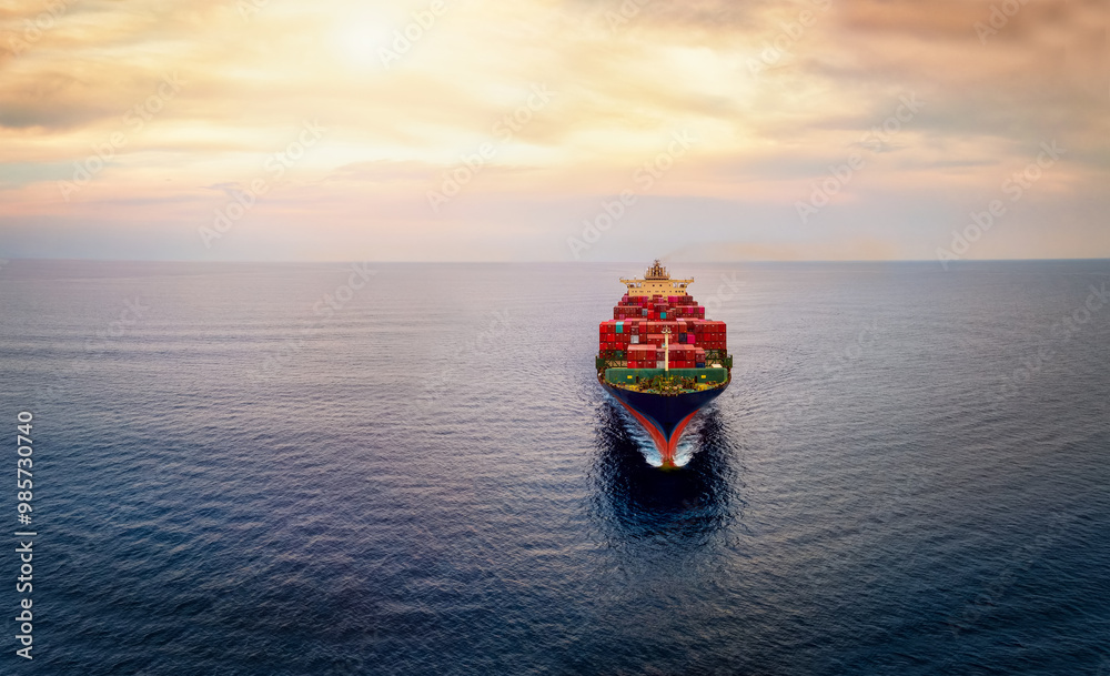 Aerial front view of a big cargo container carrier ship sailing over the ocean during sunset time with copy space