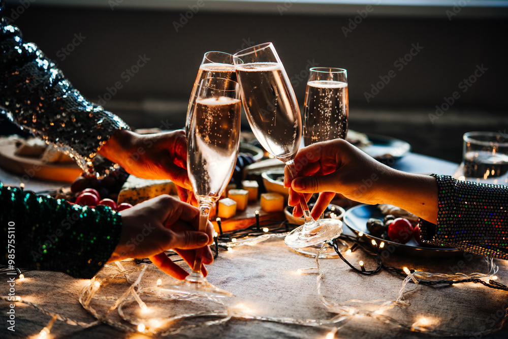 Friends celebrating Christmas or New Year eve party with champagne or sparkling wine.