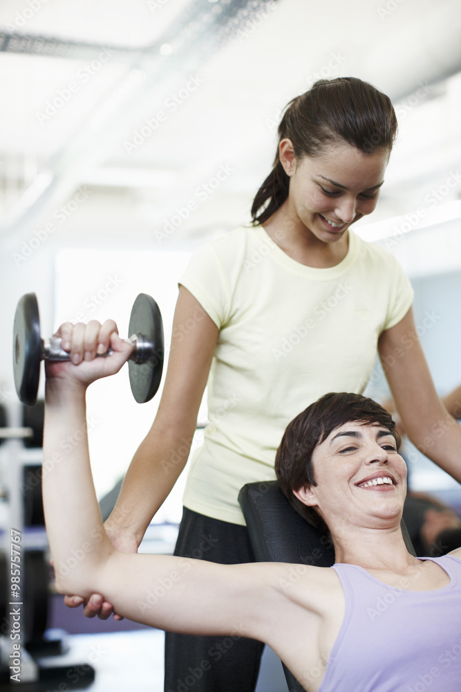 Fitness, weights and personal trainer with woman in gym for lifting with muscle strength training. Exercise, happy and coach helping athlete with bodybuilding workout with equipment in sports center. Fitness, weights and personal trainer with woman in gym for lifting with muscle strength training. Exercise, happy and coach helping athlete with bodybuilding workout with equipment in sports center.