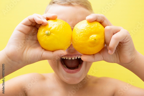 Blond-haired 7-year-old boy with two halves of natural lemons over his eyes