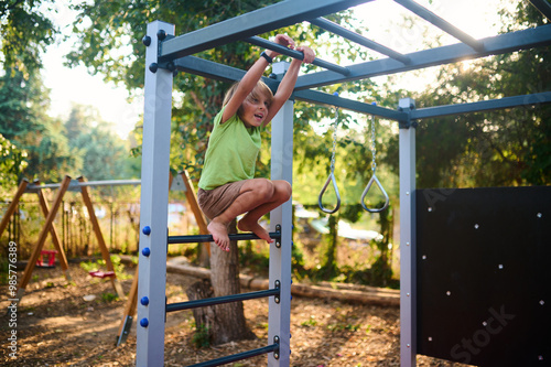 A child plays on a climbing frame in a sunny outdoor playground surrounded by trees and swings during a warm afternoon in summer