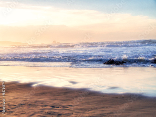 Atardecer en la playa de Santander con las olas rompiendo en la orilla