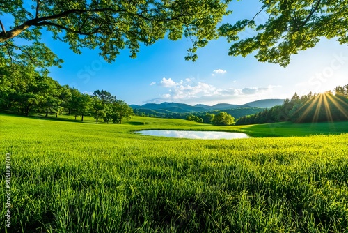 A field of green grass with a lake in the middle of it photo