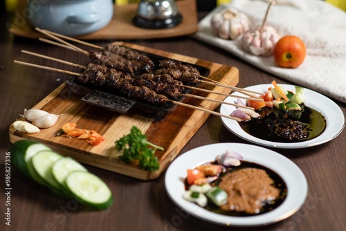 Satay: A stack of skewered satay served on a small black plate. The plate is placed on a mini wooden grill, adding a warm and authentic feel to the dish.