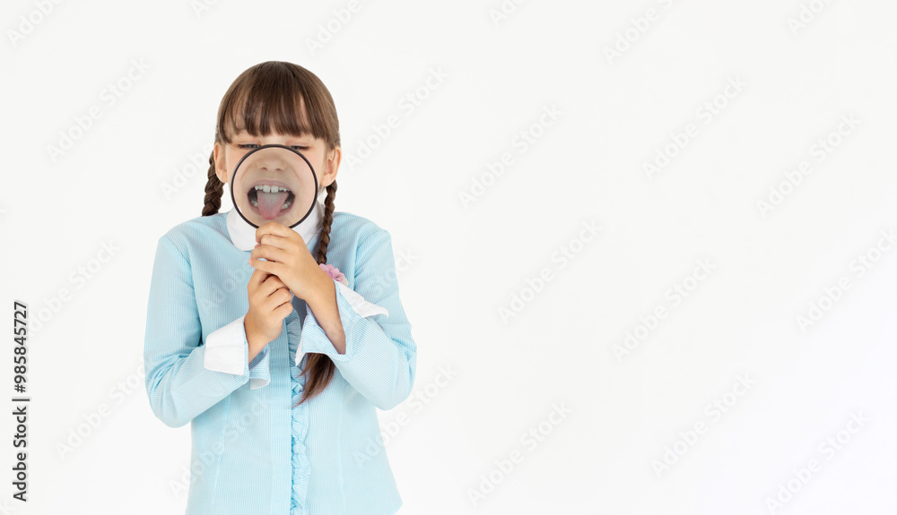 Happy little schoolgirl in uniform with magnifier on white background Happy little schoolgirl in uniform with magnifier on white background