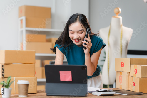 Smiling Businesswoman on Phone: A young, Asian businesswoman beams with confidence as she manages her online business, showcasing the power of technology and entrepreneurship. The scene exudes energy,