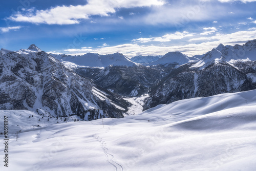 Obraz na płótnie Ski tracks on fresh show leading down to beautiful valley with snow covered mountains in the background, Winter sport in Alps, France w salonie