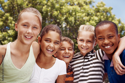 Children, hug and portrait of student friends outdoor at school together for development. Diversity, education or smile with happy boy and girl kids embracing for bonding, growth or learning