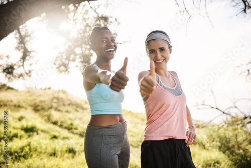 Interracial women, portrait and fitness with thumbs up in nature for good workout, exercise or training together. Young, female people or friends with smile, like emoji or yes sign for outdoor hiking