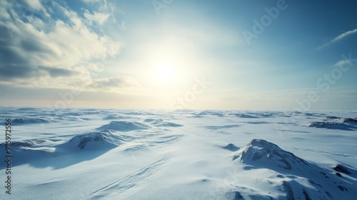 A vast snowy landscape with rolling hills under a bright blue sky with puffy white clouds.