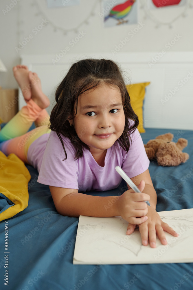Portrait of little girl looking at camera while drawing in her bedroom Portrait of little girl looking at camera while drawing in her bedroom