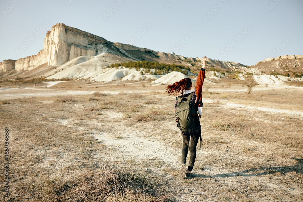 Exploring the vast desert landscape woman with backpack standing with arms outstretched in the desert wilderness Exploring the vast desert landscape woman with backpack standing with arms outstretched in the desert wilderness