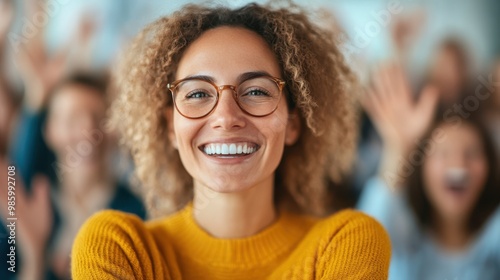 A confident woman stands smiling with arms crossed amidst a lively, cheerful crowd, radiating self-assuredness and positive vibes in a bright atmosphere.