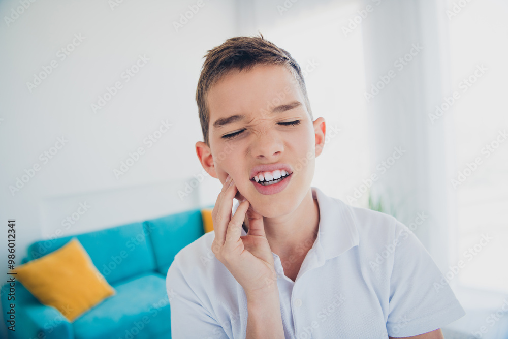 Portrait of charming little boy touch painful tooth wear t-shirt modern interior flat indoors Portrait of charming little boy touch painful tooth wear t-shirt modern interior flat indoors