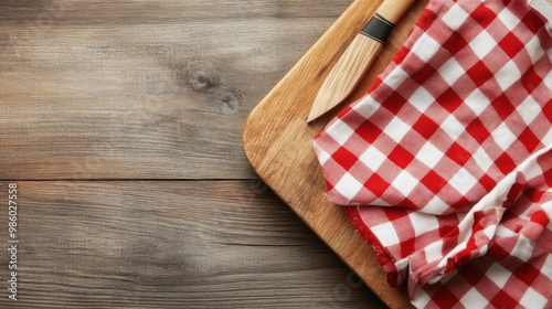 A rustic themed table presentation featuring a red checkered cloth and a wooden knife on a wooden board, creating a cozy and traditional kitchen setup.