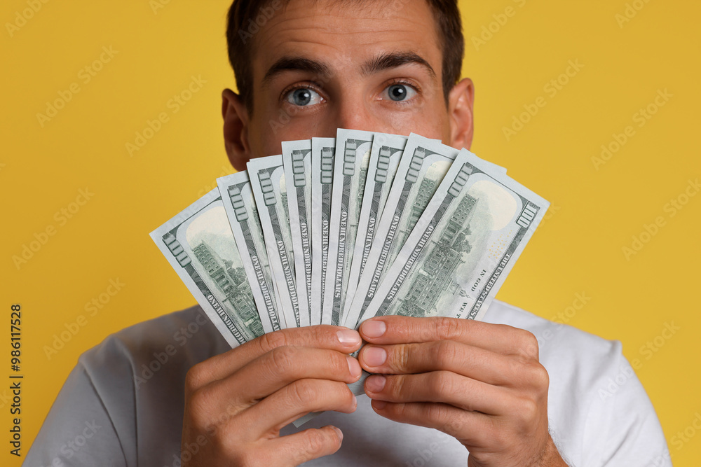 Man with dollar banknotes on yellow background Man with dollar banknotes on yellow background